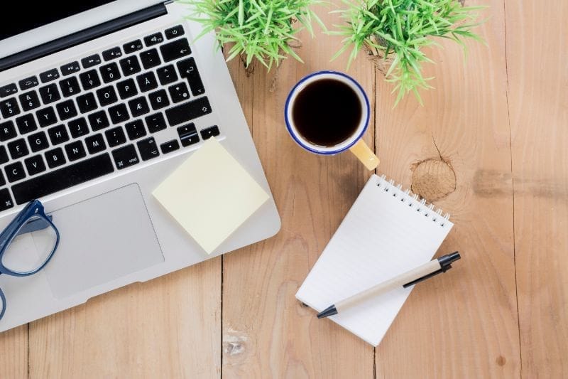 Ambiance de travail de webmaster avec un ordinateur, café et bloc-notes.