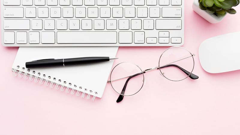 Clavier, lunettes et cahier sur un bureau - illustration pour un article expliquant pourquoi WordPress est idéal pour la création de sites web