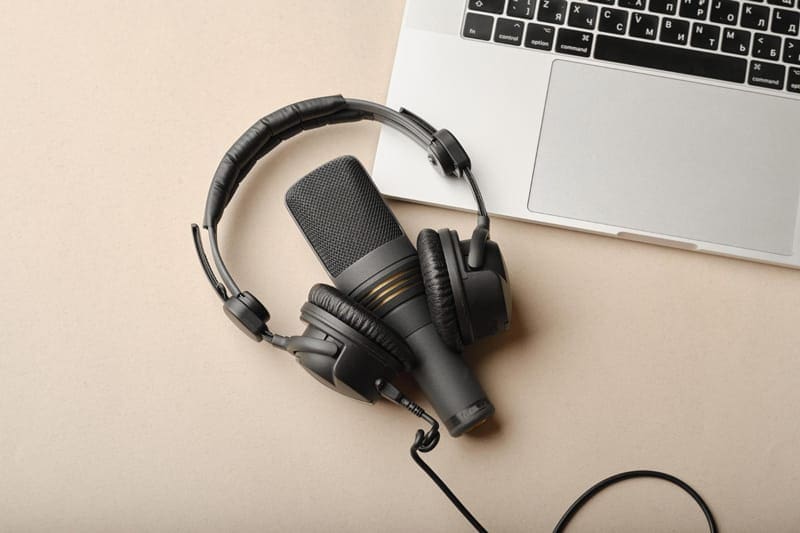 Micro et casque audio posés sur un ordinateur, représentant l’univers des podcasts.